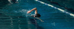 seorang wanita sedang melakukan teknik renang gaya bebas yang benar di lintasan aquatic indoor untuk renang