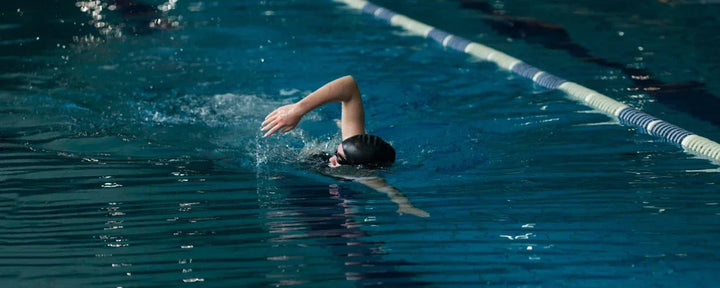 seorang wanita sedang melakukan teknik renang gaya bebas yang benar di lintasan aquatic indoor untuk renang