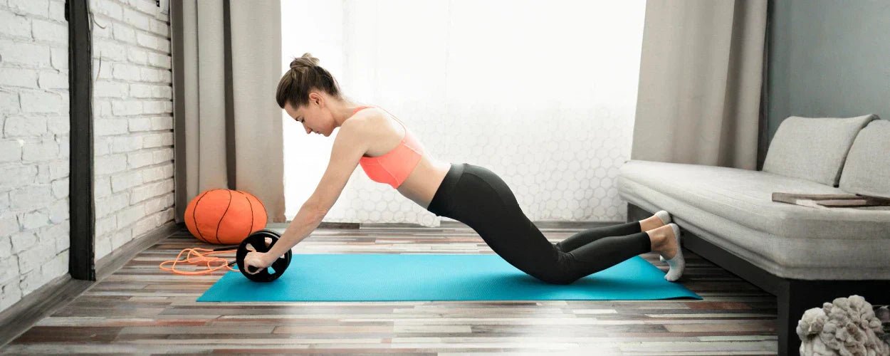 seorang wanita yang sedang berolahraga menggunakan abs roller untuk wanita guna melatih kekuatan otot perut dan keseimbangan tubuh di rumah