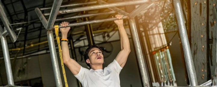Seorang pria sedang berlatih menggunakan alat pull up di rumah untuk melatih kekuatan otot tubuh bagian atas