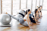 sekelompok wanita sedang berlatih Pilates dengan gym ball