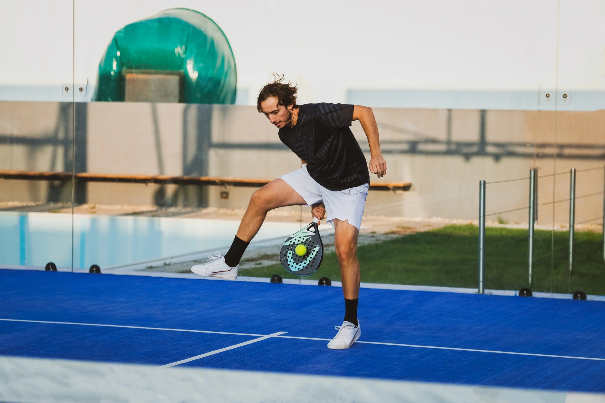 Seorang pria berlatih pukulan kreatif di lapangan biru sebagai bagian dari cara meningkatkan skill padel