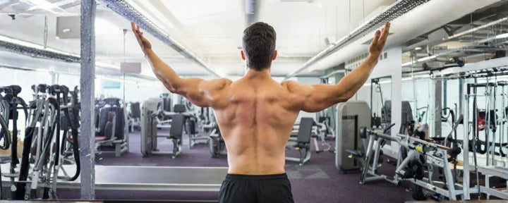 eorang pria yang sedang berolahraga di gym dengan postur tegap, menggambarkan cara menjaga kesehatan tulang punggung melalui latihan dan kekuatan otot yang seimbang