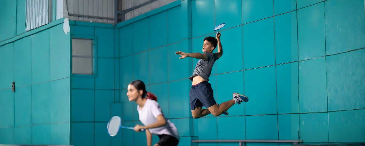 seorang atlet pria sedang mempraktikan cara smash badminton yang benar saat bermain badminton ganda campuran