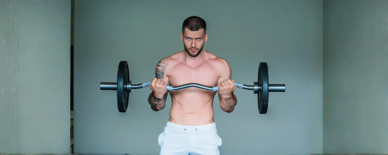 Seorang pria sedang melakukan latihan angkat beban menggunakan curl bar, menggambarkan perbedaan teknik dan fungsi pada pembahasan curl bar vs barbell bar