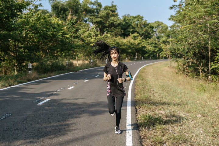 seorang wanita berpakaian hitam sedang berlari di jalan raya dengan menggunakan alat bantu di lengannya untuk mengukur vo2max