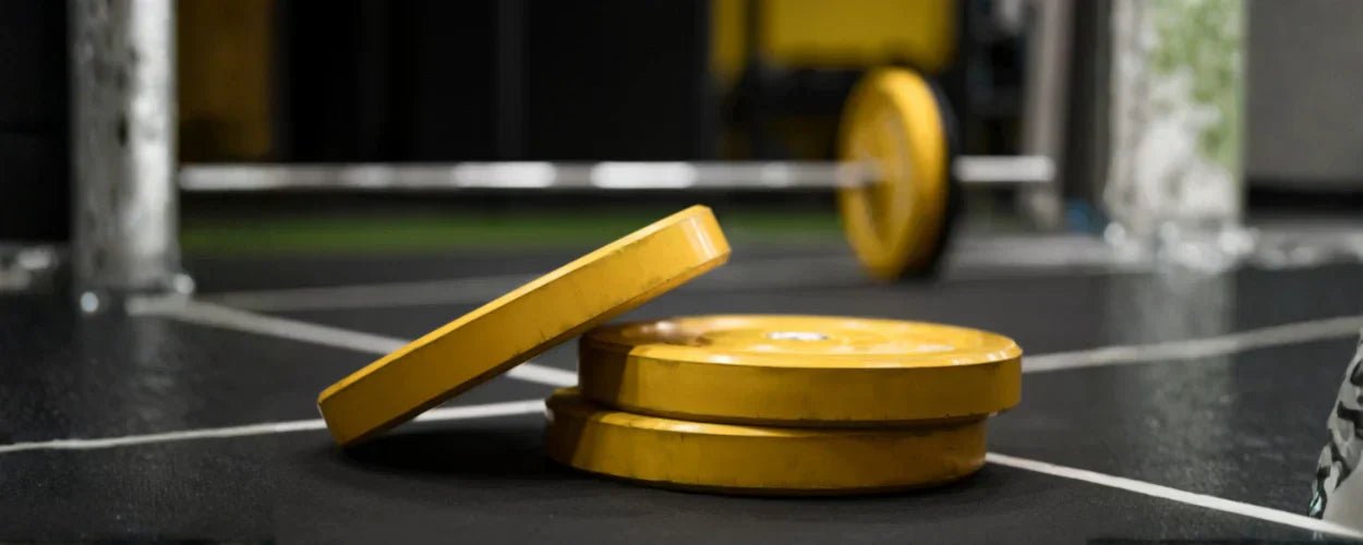 beberapa gym plates berwarna kuning yang digunakan sebagai beban tambahan dalam latihan angkat berat di gym