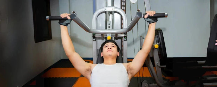 Seorang pria sedang melakukan incline bench press menggunakan mesin gym untuk melatih otot dada bagian atas