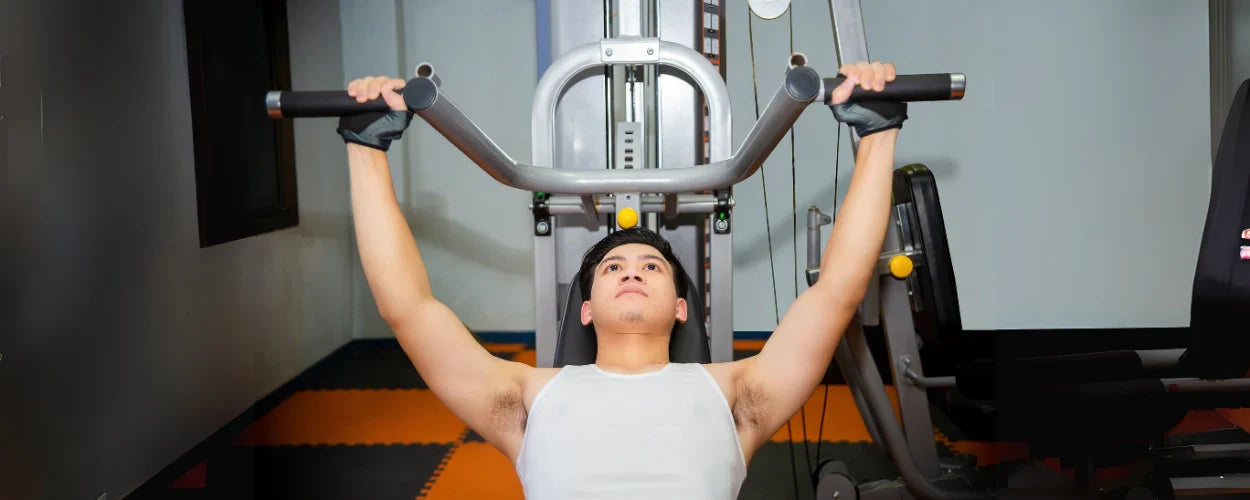 Seorang pria sedang melakukan incline bench press menggunakan mesin gym untuk melatih otot dada bagian atas