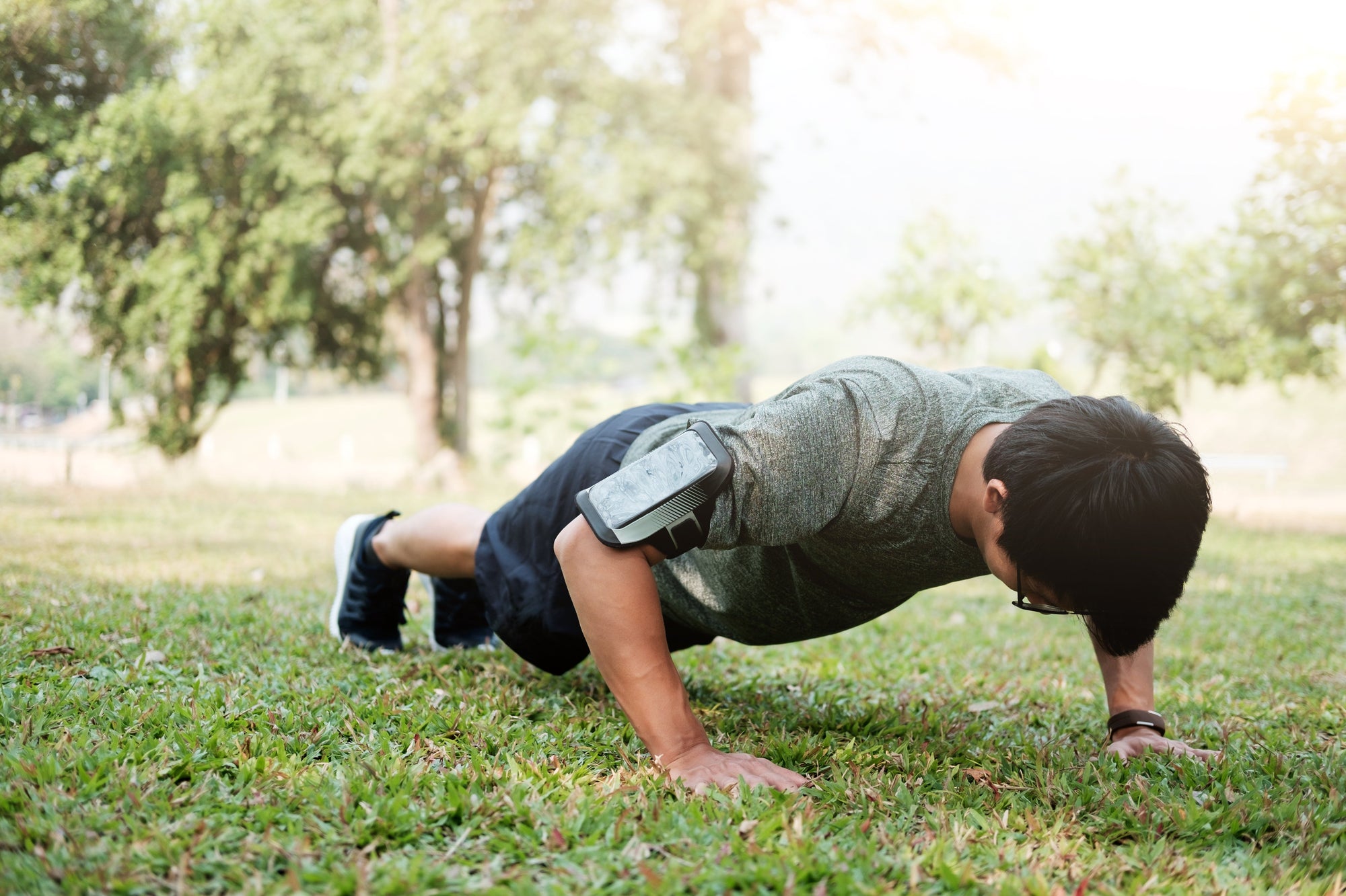 Seorang pria melakukan push-up di taman sebagai bagian dari latihan daya tahan tubuh.
