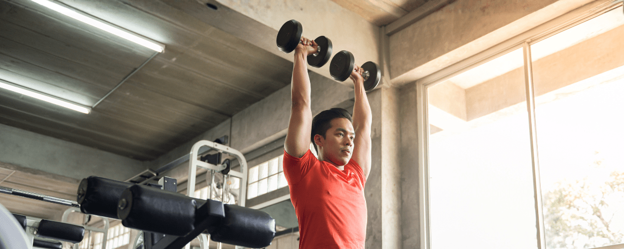 seorang pria yang sedang melakukan latihan angkat beban untuk pemula dengan menggunakan dumbbell untuk membangun kekuatan dan meningkatkan postur tubuh