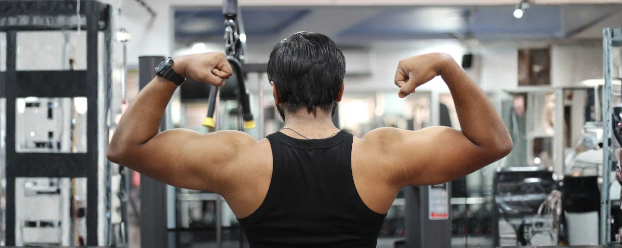 seorang pria sedang memamerkan otot punggung dan lengan setelah melakukan latihan back di gym