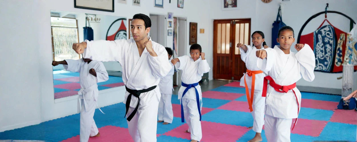sesi latihan fisik untuk Taekwondo, di mana pelatih dan murid berlatih teknik pukulan dengan fokus, disiplin, dan koordinasi di atas matras dojo