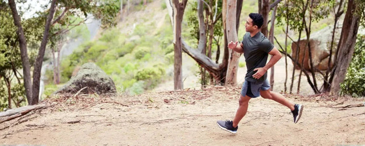 Pria sedang berlari di jalur tanah dengan intensitas terkontrol sebagai bagian dari latihan lari interval untuk meningkatkan kecepatan dan stamina
