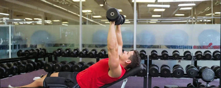 seorang pria sedang latihan triceps di gym dengan menggunakan dumbbell