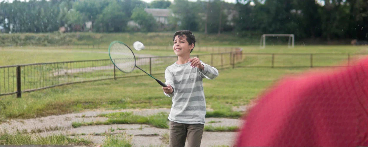 seorang anak bermain badminton di luar ruangan sebagai ilustrasi untuk menjelaskan macam-macam pukulan bulu tangkis