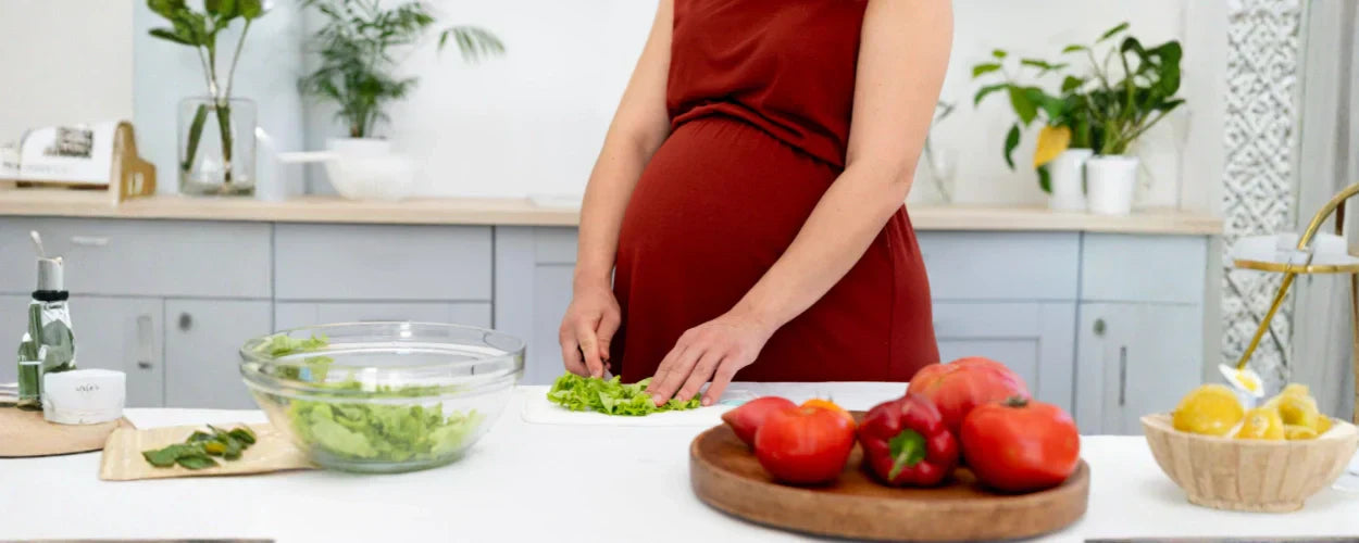 seorang ibu hamil sedang menyiapkan sayuran segar di dapur sebagai bagian dari makanan sehat untuk ibu hamil