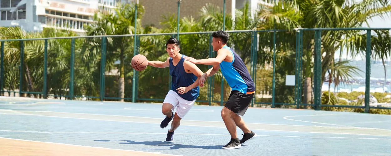 Dua pemain basket saling berhadapan untuk menunjukkan teknik man to man defense, di mana pemain bertahan fokus menjaga lawan secara langsung satu lawan satu