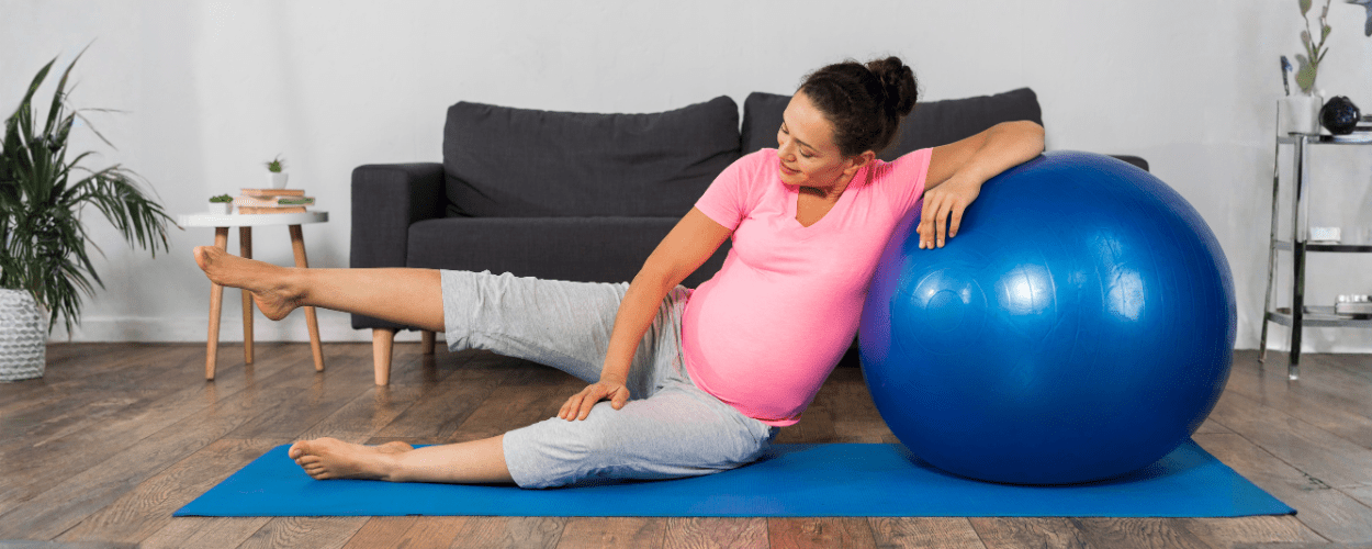 Seorang ibu hamil sedang berolahraga dengan gym ball, menggambarkan manfaat gym ball untuk ibu hamil dalam membantu menjaga kebugaran, keseimbangan, dan kenyamanan tubuh selama kehamilan