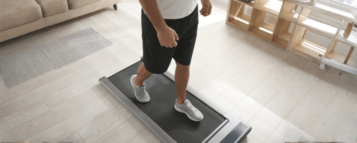 seseorang yang sedang berjalan di atas walking pad, menggambarkan manfaat jalan di walking pad untuk menjaga kebugaran dan meningkatkan kesehatan jantung secara praktis di rumah