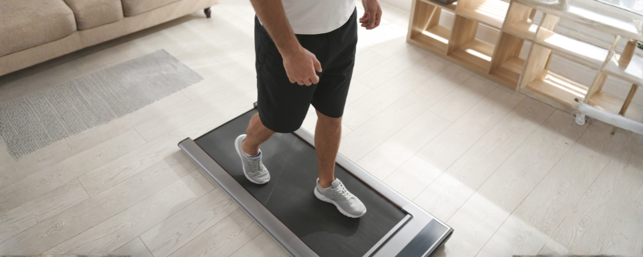 seseorang yang sedang berjalan di atas walking pad, menggambarkan manfaat jalan di walking pad untuk menjaga kebugaran dan meningkatkan kesehatan jantung secara praktis di rumah