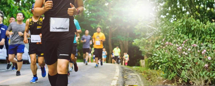 Para pelari berlari bersama di jalur outdoor yang dikelilingi pepohonan, menggambarkan bahwa marathon adalah ajang lari jarak jauh yang menuntut ketahanan fisik dan mental