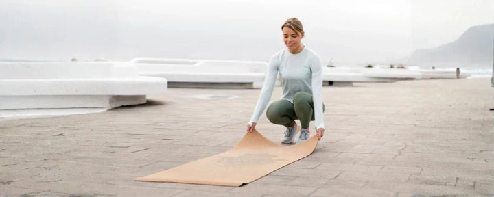 seorang wanita sedang menyiapkan matras yoga terbaik untuk berolahraga di luar ruangan dengan suasana yang tenang dan menyegarkan
