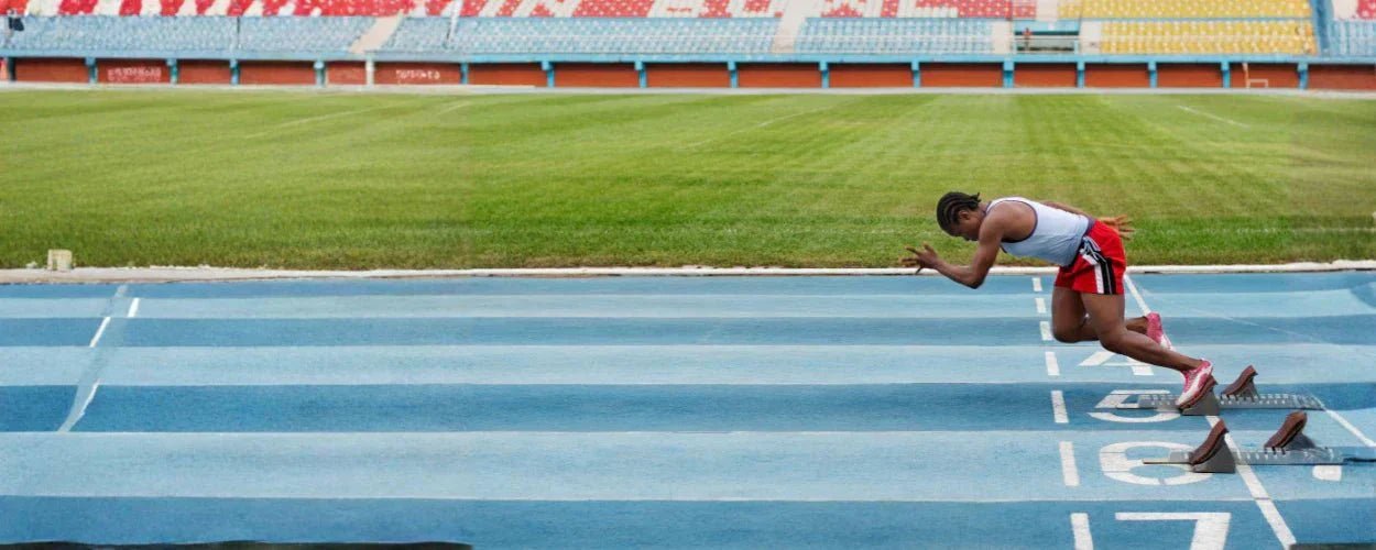 seorang pelari yang bersiap melakukan start pada lintasan atletik sebagai ilustrasi nomor lari jarak pendek