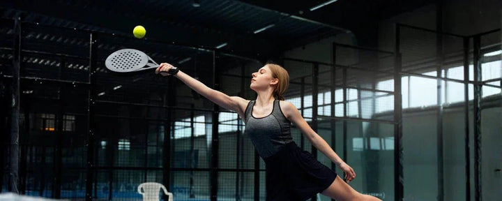 seorang wanita berbaju hitam sedang memukul bola dalam permainan olahraga padel