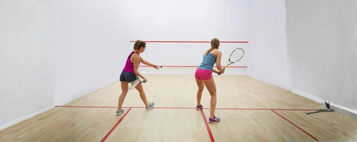 dua orang yang sedang bermain olahraga squash di dalam lapangan tertutup dengan intensitas gerak yang cepat