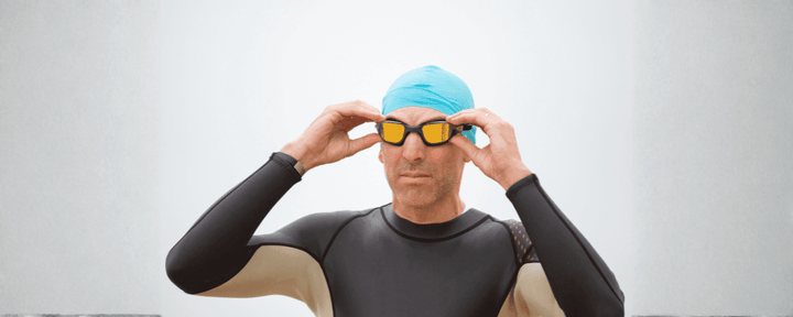 seorang pria mengenakan kacamata renang, swim cap, dan wetsuit sebagai contoh penggunaan peralatan renang yang lengkap untuk latihan atau kompetisi