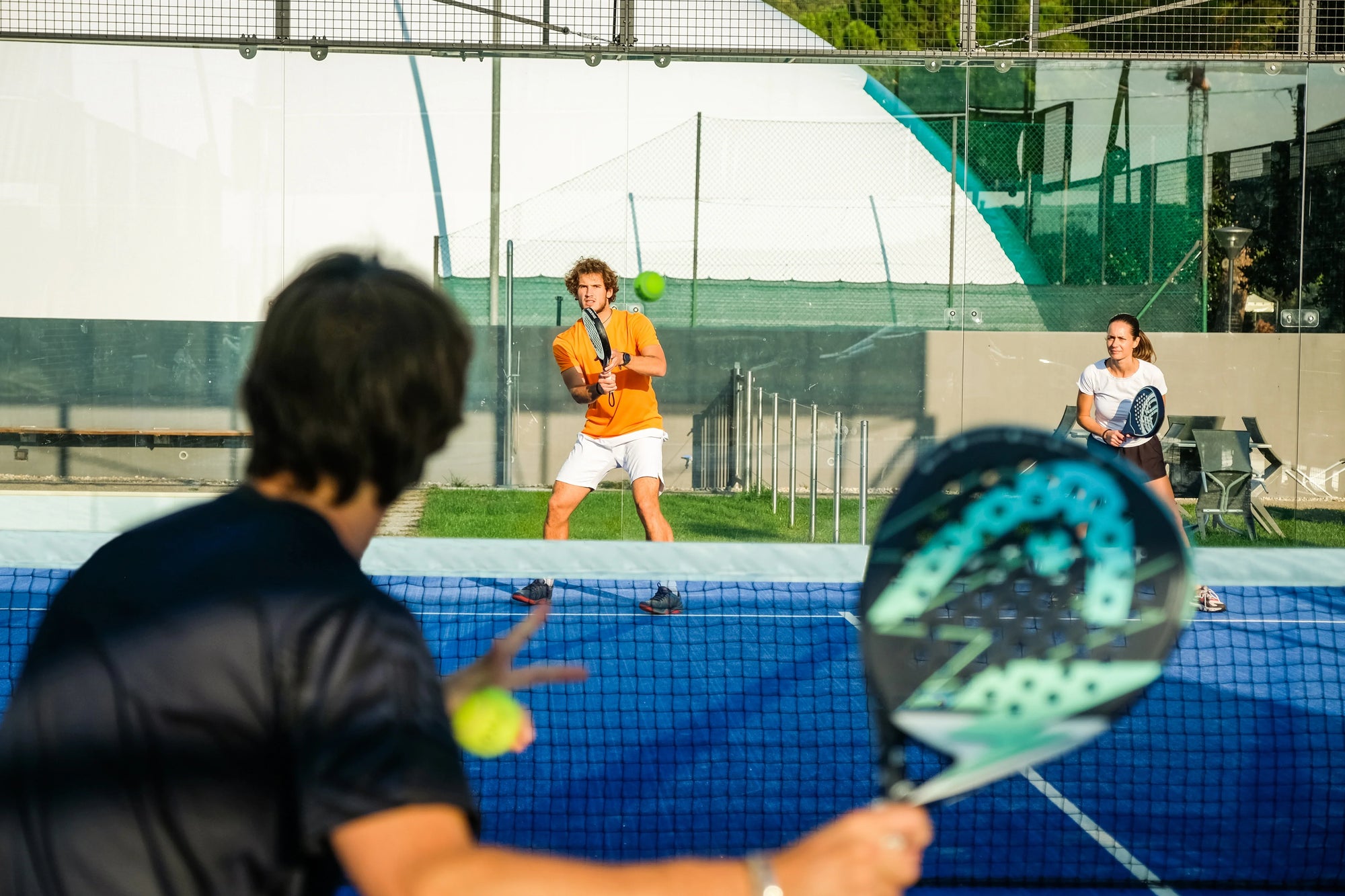 Para pemain sedang berlatih rally di lapangan sebagai contoh penerapan cara peraturan permainan padel yang benar