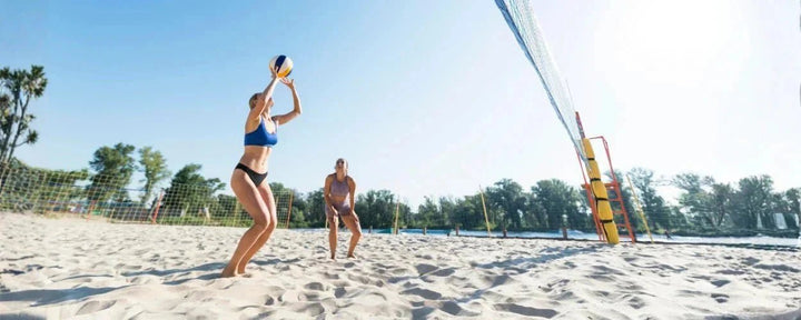 2 orang atlet voli pantai wanita sedang bermain voli pantai sesuai dengan peraturan voli pantai yang berlaku