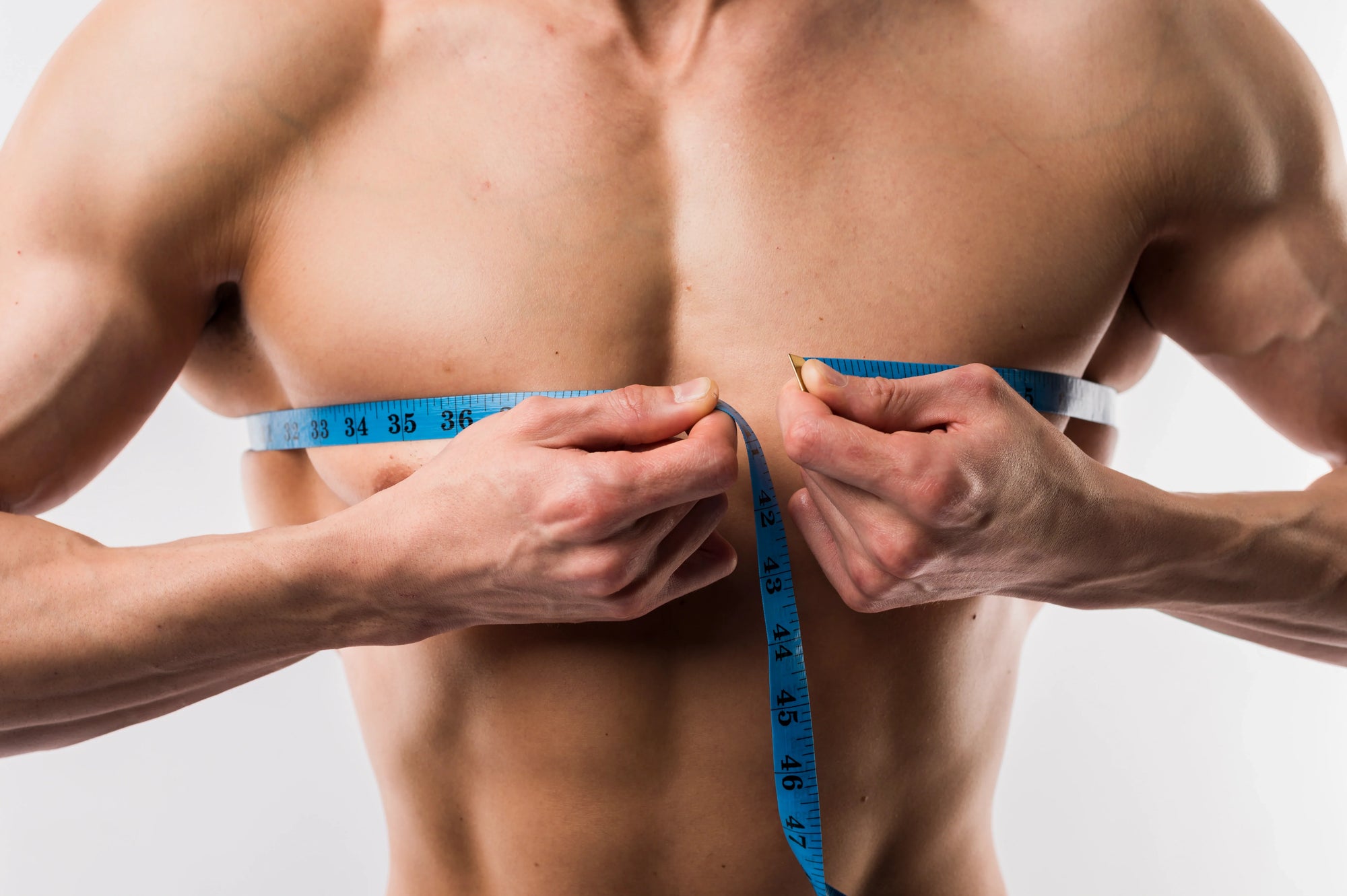 seorang pria mengukur dadanya untuk memperlihatkan perbadaan antara bulking dan cutting