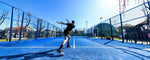 seseorang sedang bermain di lapangan biru berpagar, menggambarkan perbedaan padel dan soft tenis dari sisi lapangan serta teknik permainan yang unik pada masing-masing olahraga raket tersebut