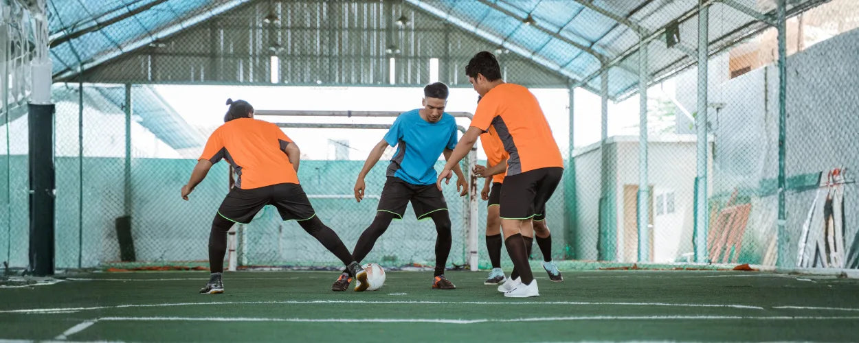 Beberapa pemain tampak berebut bola dengan intens dalam permainan futsal yang berlangsung di lapangan indoor