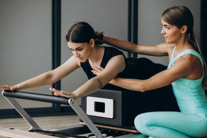seorang wanita sedang melakukan gerakan pilates bersama instrukturnya