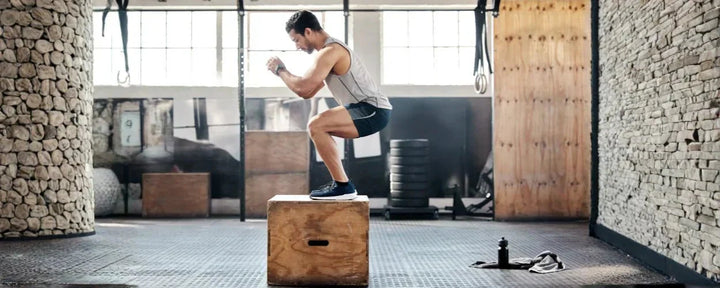 Seorang pria sedang berlatih melompat menggunakan plyo boxes untuk meningkatkan kekuatan dan eksplosivitas otot kaki di gym