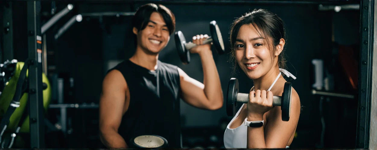 dua orang yang sedang berlatih beban di gym sebagai bagian dari pola latihan gym terbaik untuk membentuk otot dan meningkatkan kebugaran tubuh