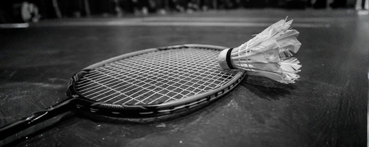 raket dan shuttlecock yang tergeletak di lapangan, menggambarkan semangat dan perjalanan panjang dalam sejarah bulu tangkis di Indonesia