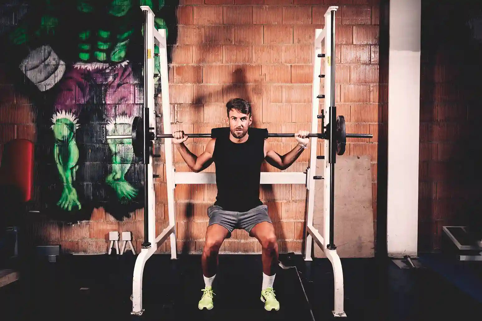 Seorang pria sedang melakukan latihan kekuatan dengan Smith Machine Bench Press untuk melatih otot dada dan bahu di gym