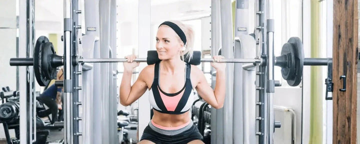 Seorang wanita sedang melakukan Smith Machine Squat di gym.