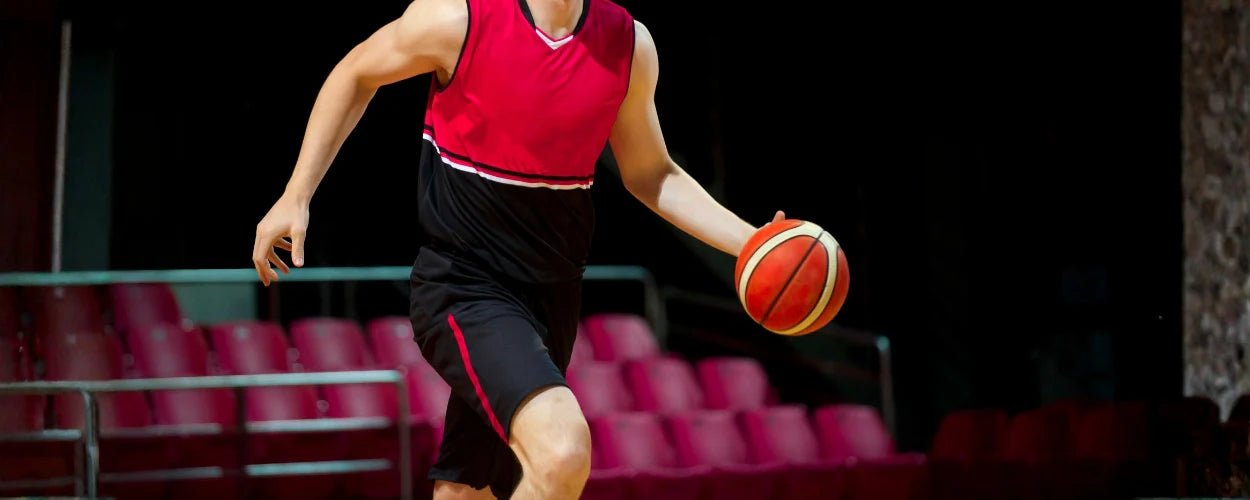 seorang atlet sedang men-dribbling bola basket sebagai salah satu teknik dasar bola basket