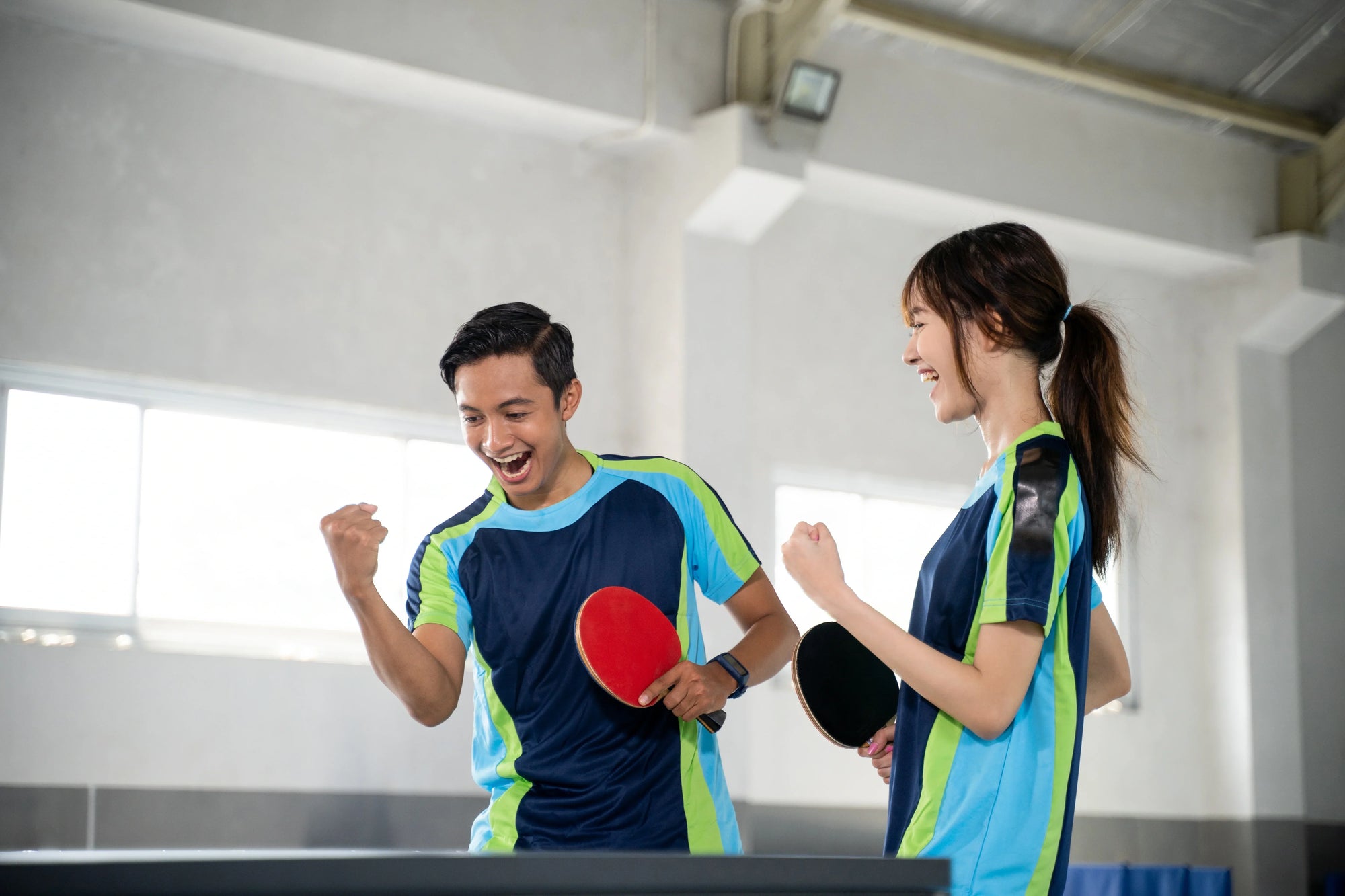 sepasang atlet tenis meja tampak bahagia setelah berhasil mempraktikan teknik dasar tenis meja