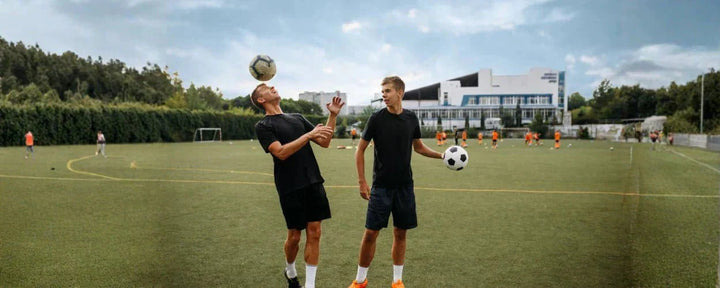 Dua pria sedang berlatih teknik menyundul bola di lapangan sepak bola untuk meningkatkan kontrol dan akurasi arah bola di udara