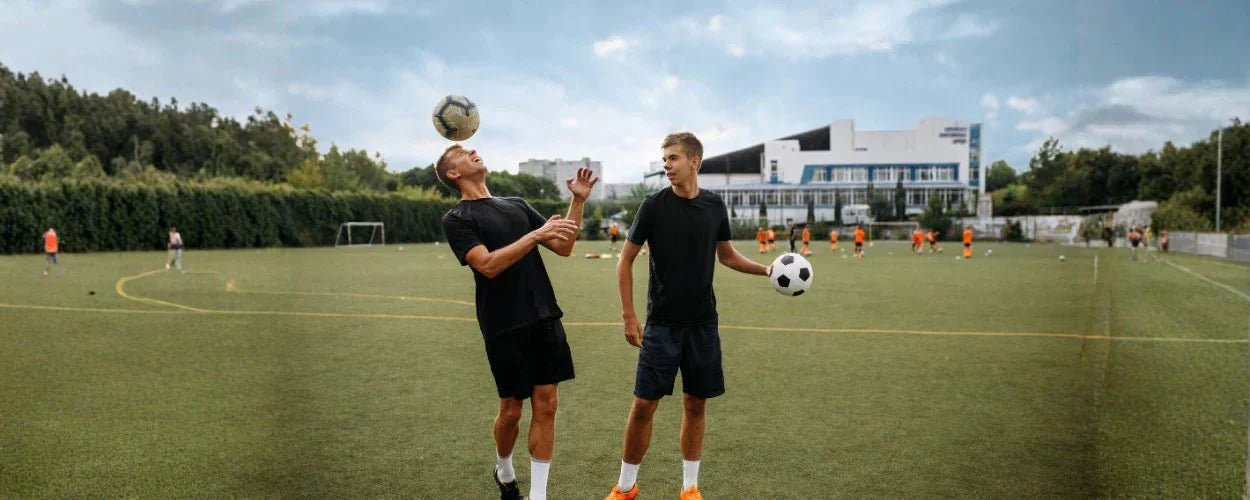 Dua pria sedang berlatih teknik menyundul bola di lapangan sepak bola untuk meningkatkan kontrol dan akurasi arah bola di udara