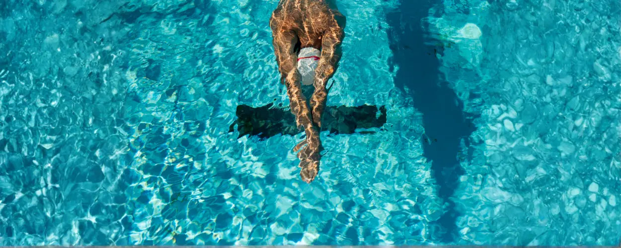 seorang perenang yang meluncur di permukaan air dengan posisi tubuh sejajar dan tangan lurus ke depan, menggambarkan awal gerakan dalam teknik renang gaya dada