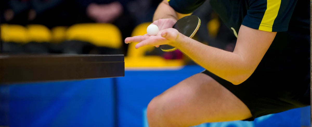 Seorang pemain sedang bersiap melakukan servis dengan posisi tangan dan bet yang menunjukkan penerapan teknik spin dalam tenis meja