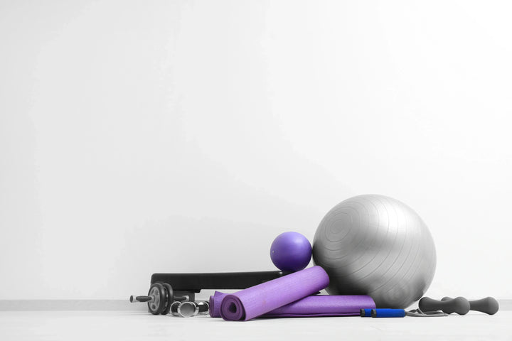 Berbagai perlengkapan olahraga seperti bola, matras, dan dumbbell.