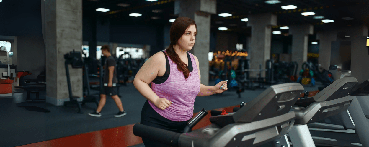 Wanita sedang berolahraga di gym menggunakan treadmill untuk berat badan 150 kg yang kokoh dan aman untuk mendukung program penurunan berat badan.
